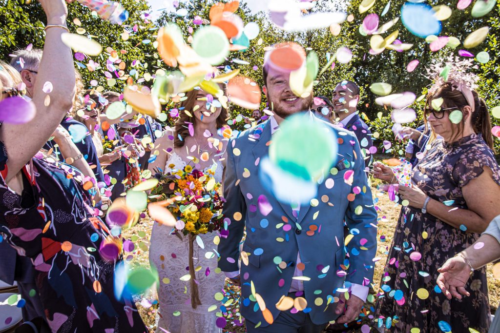 Hertfordshire wedding photographer the bride and groom are surrounded by wedding confetti