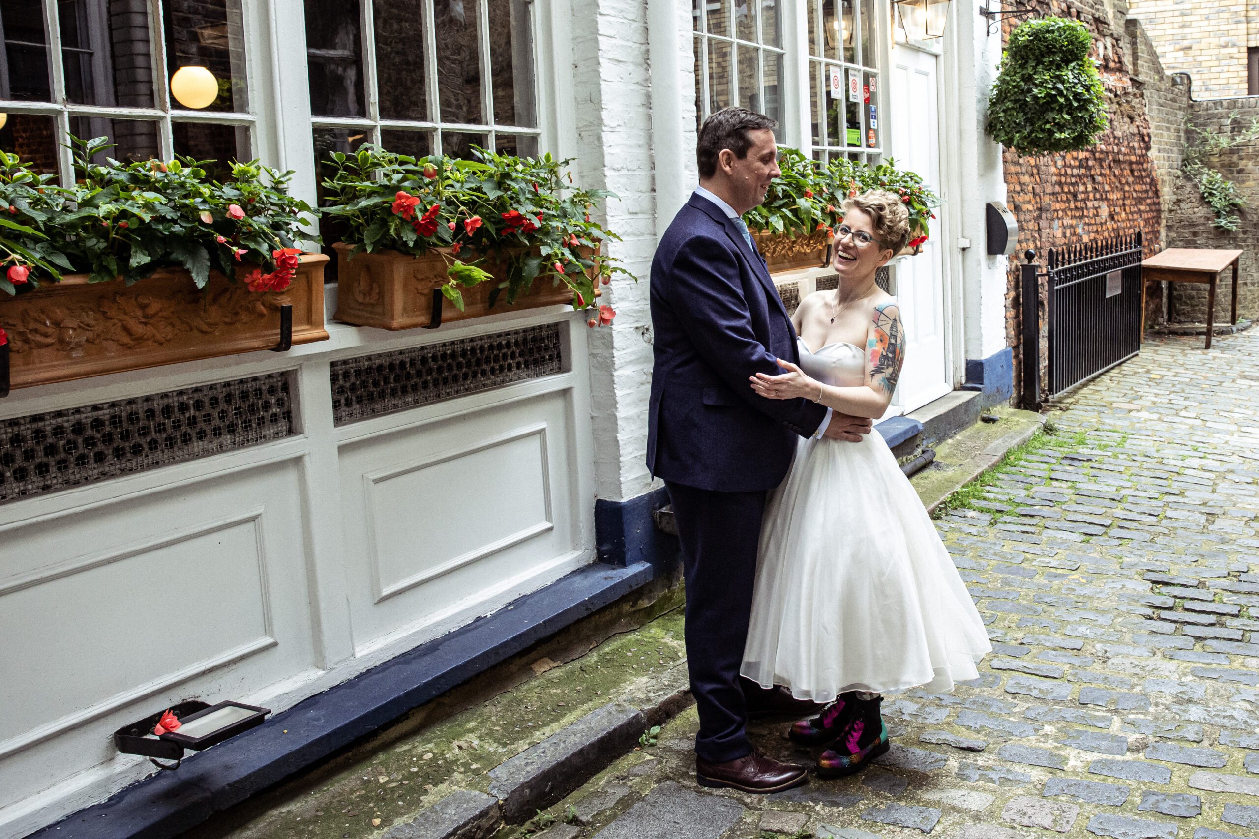 Bride and groom pose in an alleyway lined with flowers in clerkenwell london