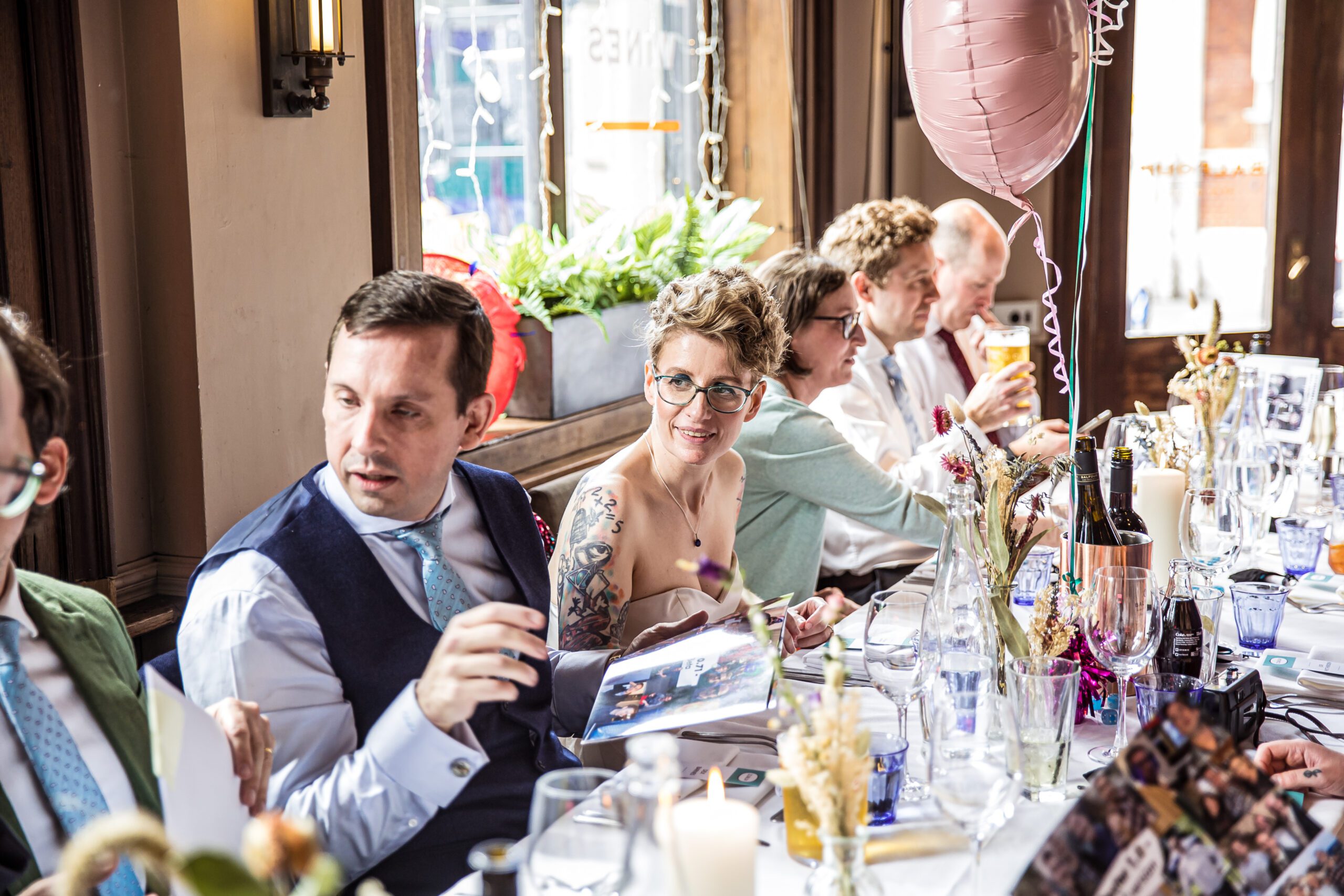 A bride smiles at her guests as she is seated at her wedding g breakfast at Balfour St Barts
