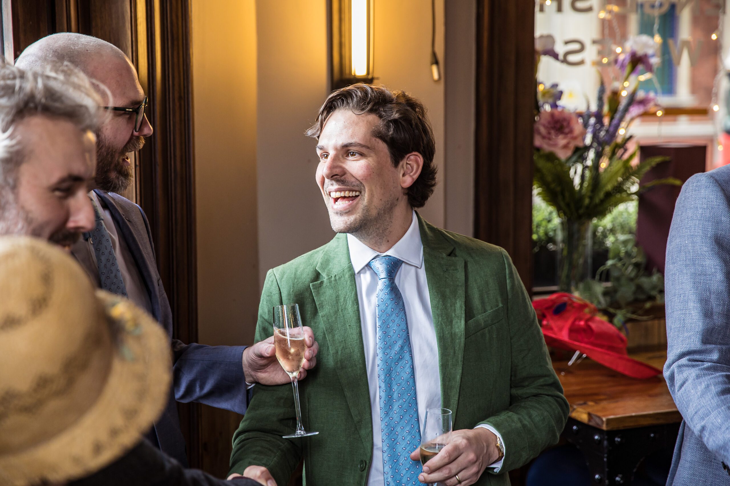 Brother of the groom dressed in a green suit shares a joke at Balfour St Barts wedding